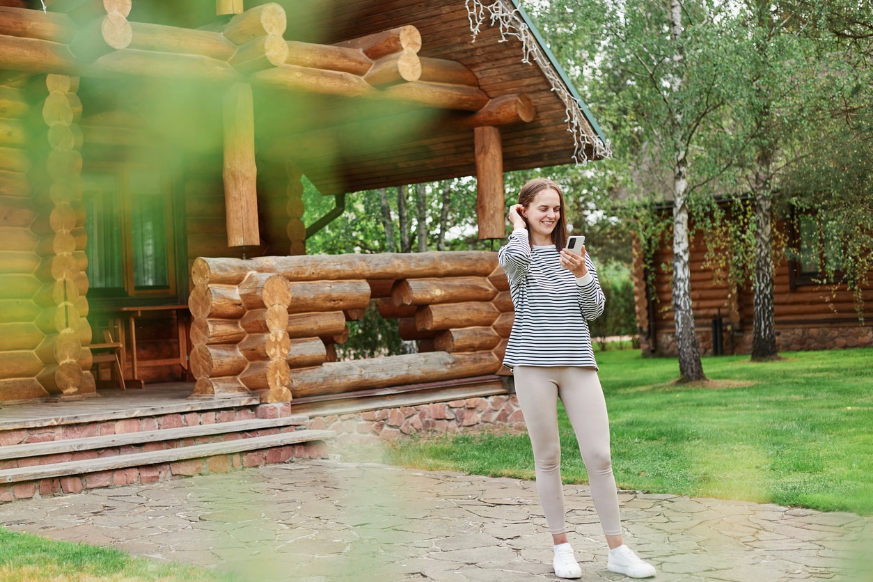 Woman Outside Log Home Sending Images For Estimate to Log Masters Restorations
