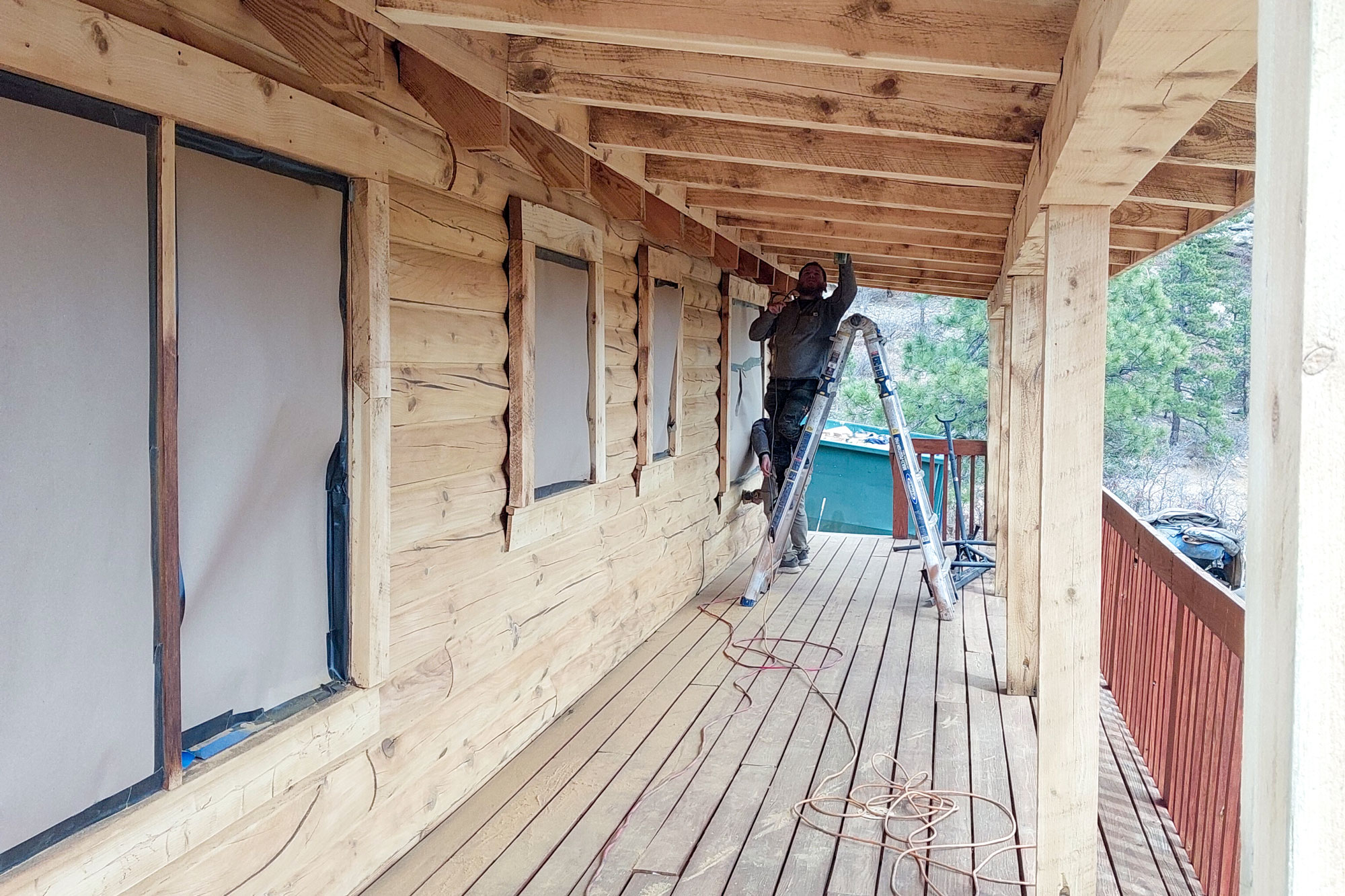 Log Master working on chinking the side of a cabin with tan chinking.