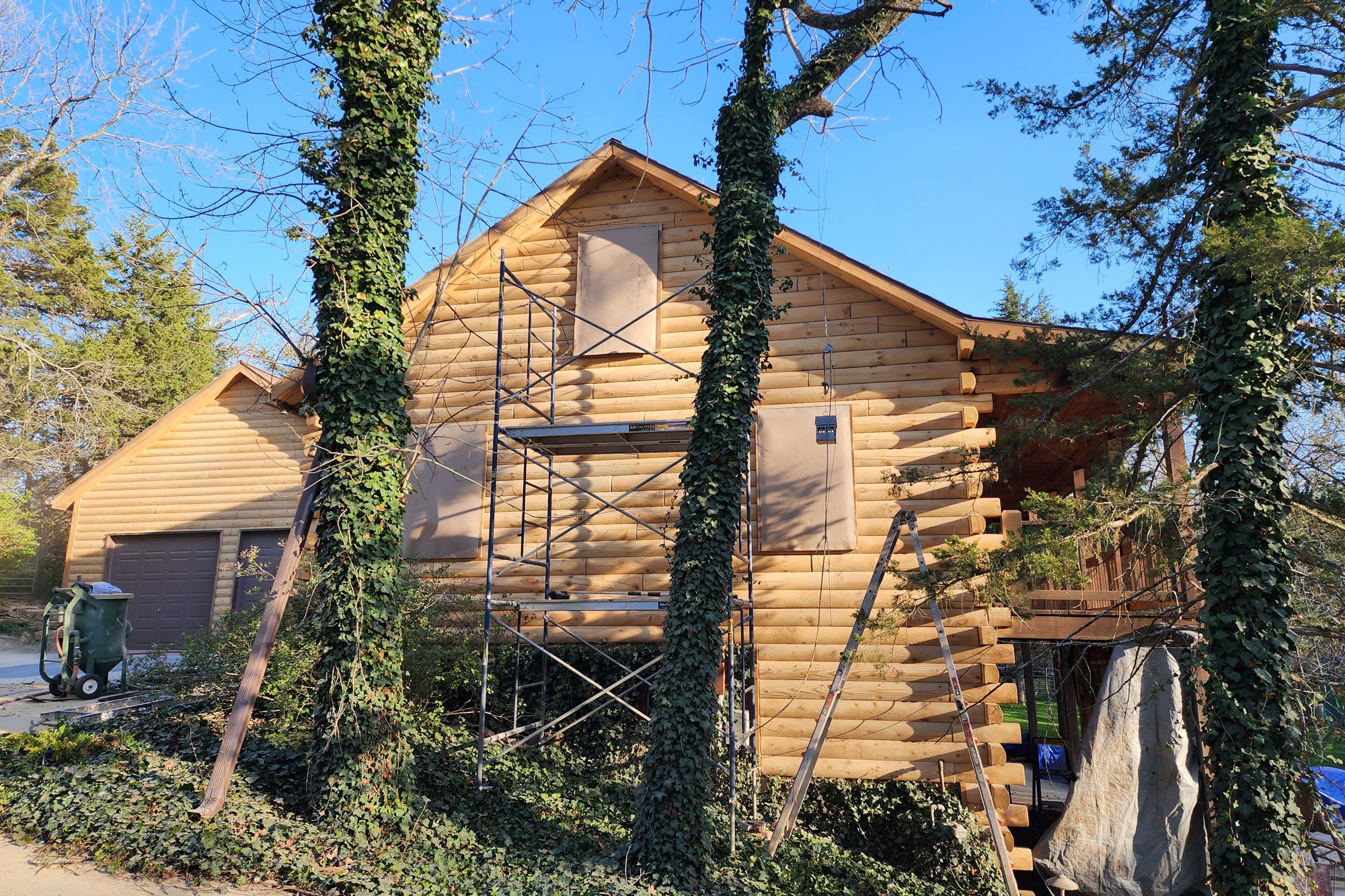 Log Masters crew using the PRD masking method to protect windows and trim during log home media blasting and restoration prep